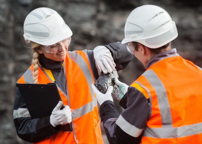 Two speacialists examining coal at an open pit